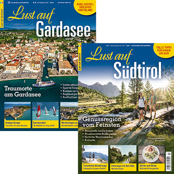 Zwei Reisemagazine: 'Lust auf Gardasee' mit Luftaufnahme einer Stadt und 'Lust auf Südtirol' mit Wanderern auf Bergweg vor Bergen.